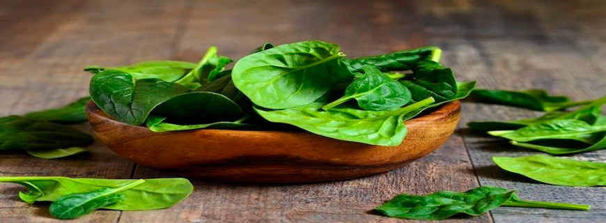 brown bowl of spinach leaves on table